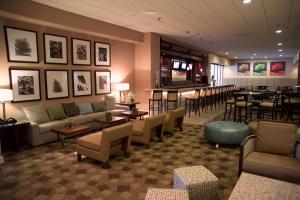 a waiting room with couches and tables and chairs at DoubleTree by Hilton St. Louis at Westport in Maryland Heights