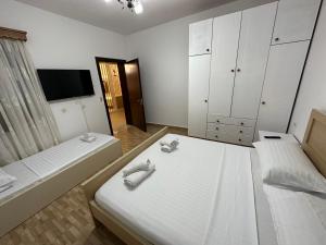 a bedroom with two beds and a flat screen tv at Elby Apartments in Berat
