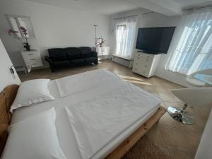 a bedroom with a white bed and a television at Hotel la Perla in Meersburg