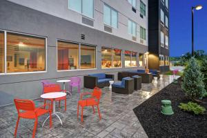 une terrasse avec des chaises et des tables colorées en face d'un bâtiment dans l'établissement Tru By Hilton Syracuse-Camillus, à Camillus