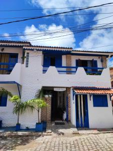 a white house with blue doors and a palm tree at Ganesha Hostel in Pipa +22 photos