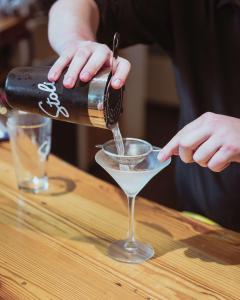 una persona vertiendo una bebida en un vaso de martini en Hotel Skyler Syracuse, Tapestry Collection by Hilton, en Syracuse