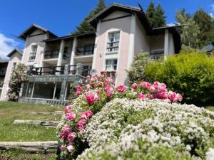 una casa con flores rosas delante de ella en Aldea Andina Hotel&Spa en San Carlos de Bariloche