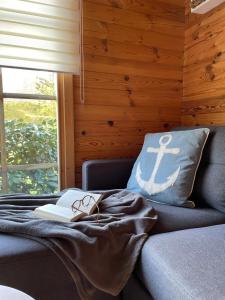 a room with a couch and a pillow with a book at TinyHouse Meereszauber- ruhige Lage, eigener Garten, Grill in Wolgast