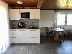 a kitchen with white cabinets and a table with a sink at Chata Trhovky 1 in Milešov