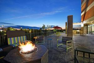 a fire pit on a patio with chairs and tables at Home2 Suites By Hilton Utica, Ny in Utica
