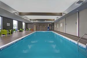 a swimming pool with blue water in a building at Home2 Suites By Hilton Utica, Ny in Utica