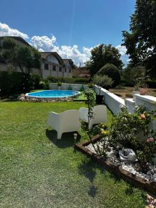 a yard with two white chairs and a pool at Galleno house in Galleno
