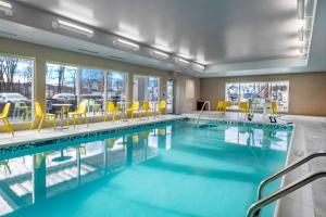 a swimming pool with yellow chairs and tables in a building at Home2 Suites By Hilton Wayne, NJ in Wayne