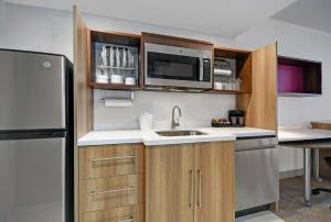 a kitchen with a sink and a refrigerator at Home2 Suites By Hilton Utica, Ny in Utica