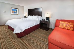 a hotel room with a bed and a red couch at Hampton Inn Tulsa/Broken Arrow in Broken Arrow