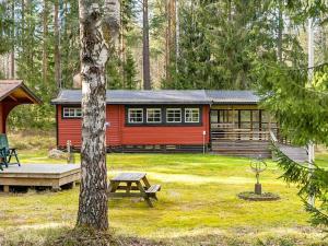 een rode hut met een picknicktafel ervoor bij Holiday home Rejmyre III in Rejmyre