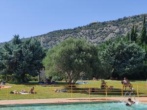 un groupe de personnes se posant dans l'herbe près d'une piscine dans l'établissement Le Romarin, à Beaumes-de-Venise