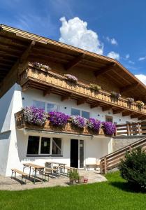 ein weißes Gebäude mit lila Blumen auf dem Balkon in der Unterkunft Gruppenhaus Alpenglück in Kirchdorf in Tirol