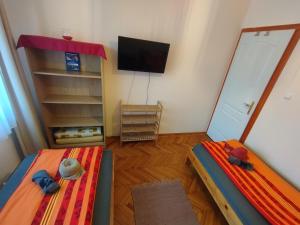 Habitación pequeña con 2 camas y TV. en Liget Szálláshely, en Berettyóújfalu