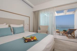 a hotel room with a bed with a tray of fruit on it at Mirage Bleu Hotel in Tragaki