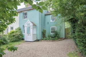 a blue house with a white door at Phoenix Cottage in Beccles