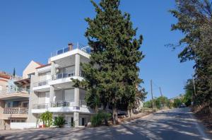 un edificio de apartamentos blanco con un árbol delante en Unique, elegant Bourtzi View Villa en Nafplio