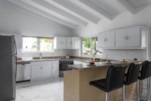 a kitchen with white cabinets and a black refrigerator at *NEW 3BR 2.5BA Villa w/Pool in Palm Beach in Palm-Eagle Beach