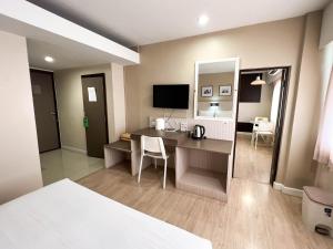 ein Hotelzimmer mit einem Schreibtisch und einem Schlafzimmer in der Unterkunft Srivichai Hotel in Nakhon Ratchasima