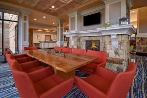 uma grande sala de jantar com uma grande mesa de madeira e cadeiras vermelhas em Hilton Garden Inn Twin Falls em Twin Falls