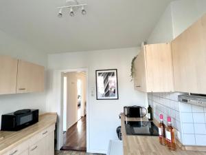 - une cuisine avec des murs blancs et des placards en bois dans l'établissement Zentrale Apartments im Herzen vom Bremerhaven, à Bremerhaven