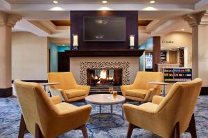 a lobby with a fireplace and chairs and a tv at Hilton Garden Inn Valencia Six Flags in Valencia