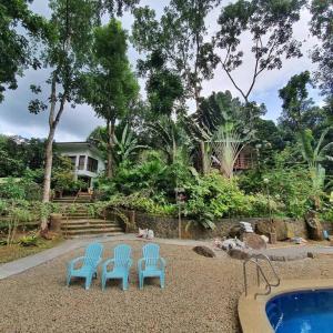 drie blauwe stoelen en een zwembad in een tuin bij Antipolo Cabin Getaway in Antipolo