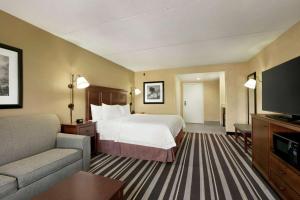 une chambre d'hôtel avec un lit, un canapé et une télévision dans l'établissement Hampton Inn Washington-Dulles International Airport South, à Chantilly