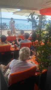 eine Gruppe von Menschen, die am Strand an Tischen sitzen in der Unterkunft Hotel la Perla in Meersburg