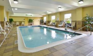 una piscina en el vestíbulo del hotel con sillas y mesas en Hampton Inn Utica en Utica