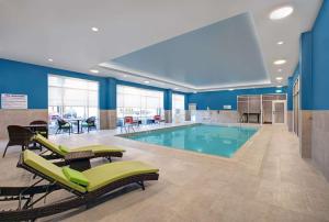 a swimming pool with lounge chairs and a table at Hampton Inn & Suites By Hilton Waterloo St. Jacobs in Waterloo