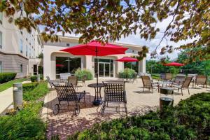 un patio con mesas y sillas y sombrillas rojas en Hampton Inn & Suites Leesburg, en Leesburg