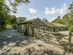 an old stone barn with a wooden gate next to a road at Egg Pudding Stone in Grange Over Sands