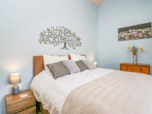 a bedroom with a white bed with a tree on the wall at Egg Pudding Stone in Grange Over Sands