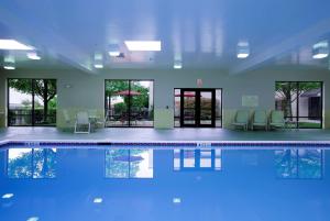 una piscina con sillas, mesas y ventanas en Hampton Inn Woodbridge en Woodbridge