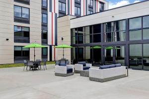 a building with chairs and tables and green umbrellas at Hampton Inn St. Catharines Niagara in St. Catharines