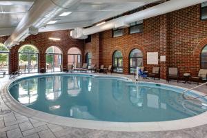 a large swimming pool in a building with a brick wall at Embassy Suites Williamsburg in Williamsburg