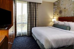 um quarto de hotel com uma cama e uma televisão de ecrã plano em Embassy Suites Williamsburg em Williamsburg
