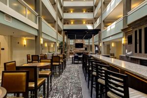 um restaurante com mesas e cadeiras e um bar em Embassy Suites Williamsburg em Williamsburg