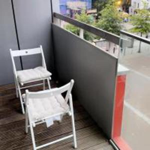 a balcony with two white chairs and a window at Tee SweetLux Apartment In Canning Town in London
