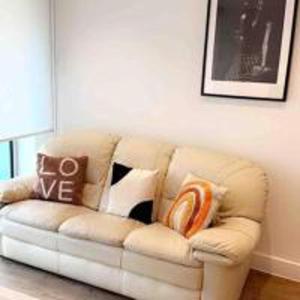 a white couch sitting in a living room with pillows at Tee SweetLux Apartment In Canning Town in London