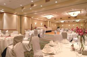 - une salle de banquet avec des tables blanches, des chaises et des fleurs dans l'établissement Hilton Garden Inn Edmonton International Airport, à Leduc