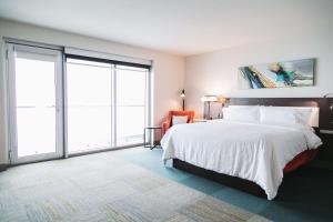 a bedroom with a large bed and large windows at Hilton Garden Inn Fredericton in Fredericton