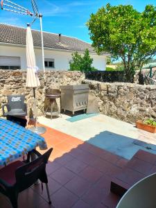 un patio con una mesa, una sombrilla y una pared de piedra en CASA DE MADEIRA E PEDRA, en Afife