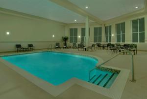 a large swimming pool in a building with tables and chairs at Hilton Garden Inn Ottawa Airport in Ottawa