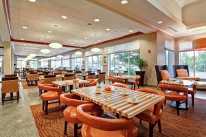 a restaurant with wooden tables and chairs and windows at Hilton Garden Inn Ottawa Airport in Ottawa