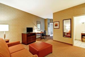 a living room with a couch and a desk with a television at Hilton Garden Inn Ottawa Airport in Ottawa