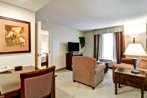 a living room with a desk and a chair and a room at Homewood Suites by Hilton Sudbury in Sudbury