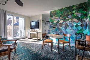 a living room with a table and chairs and a tv at Canvas Moncton, Tapestry Collection By Hilton in Moncton
